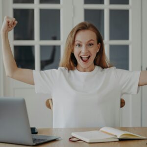 Excited woman gestures power working on project online from home. Concept of win and success.