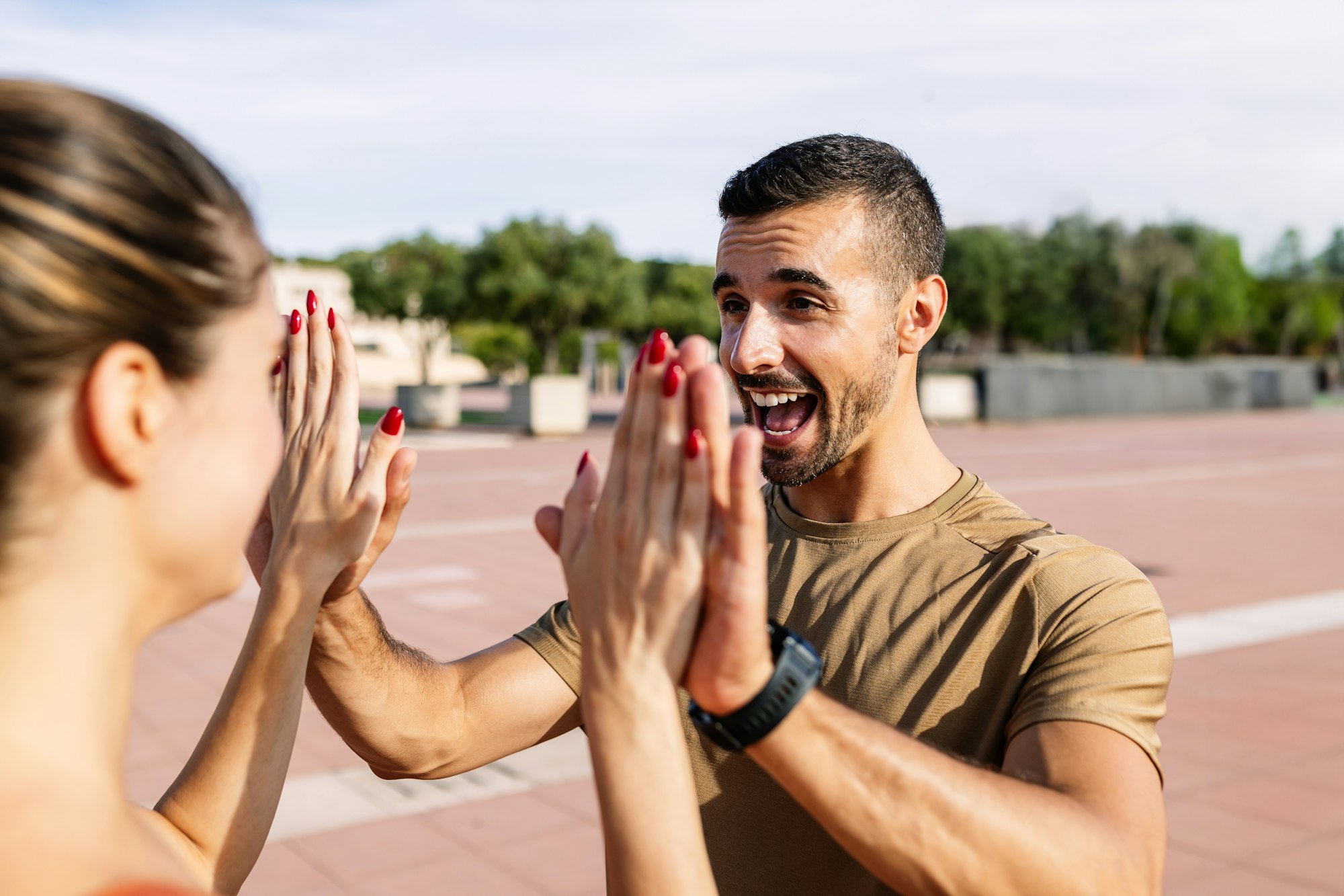 Young adult man doing high five to female friends for sport motivation